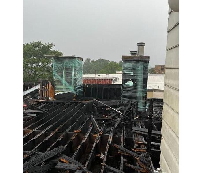 A picture containing a roof top of a building that was damaged by fire, soot, and smoke